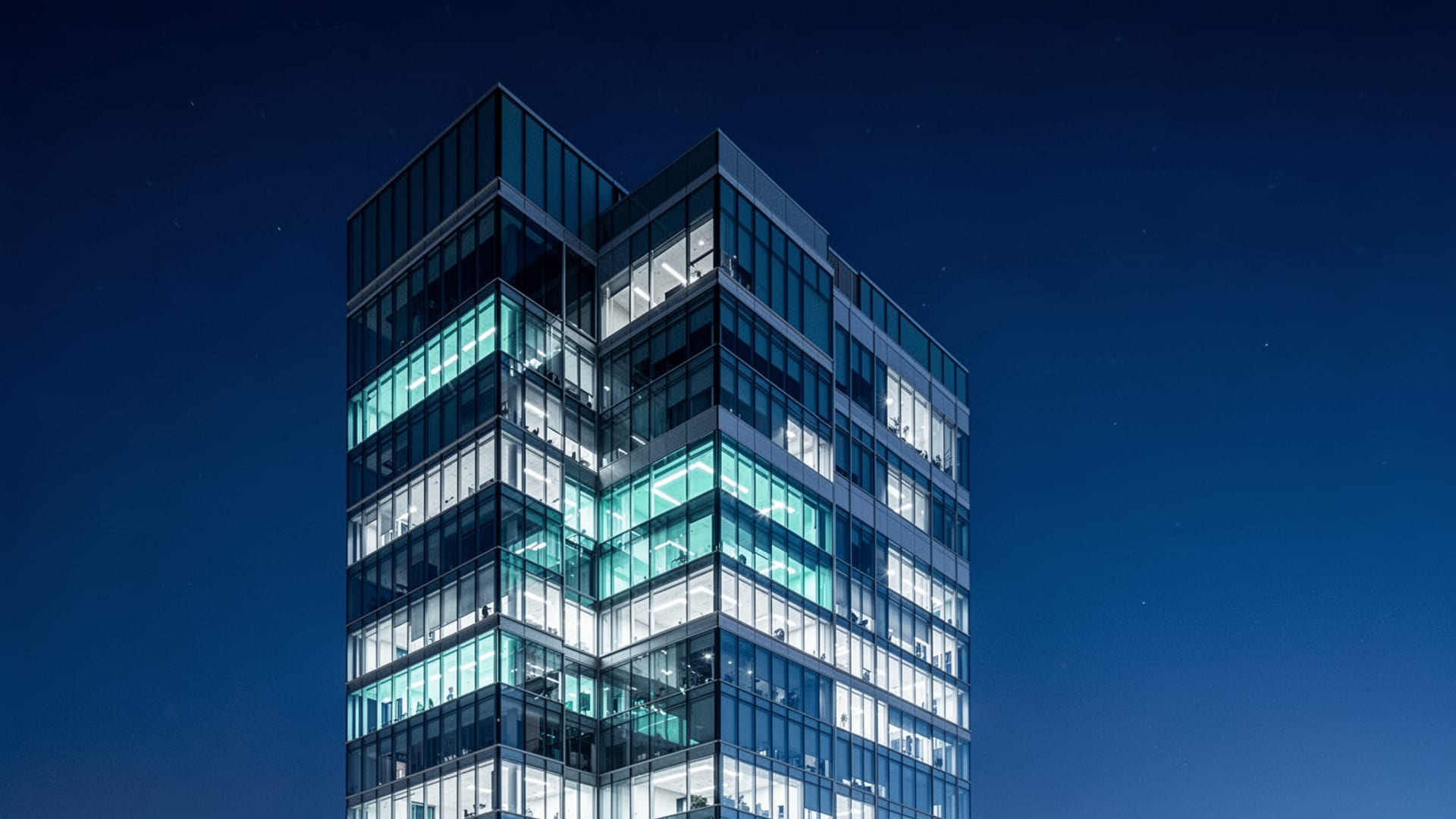 Modern glass office tower at dusk, deep blue sky